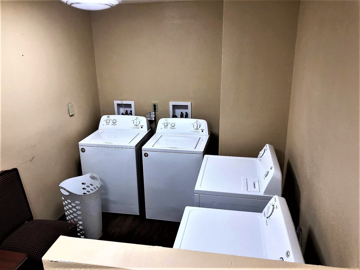 A small laundry room with two washers and two dryers alongside a laundry basket.