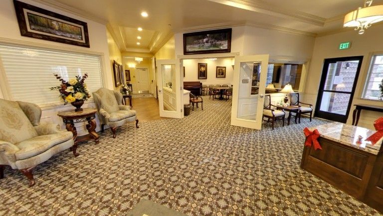 A well-decorated lobby with chairs, tables, and patterned carpeting.