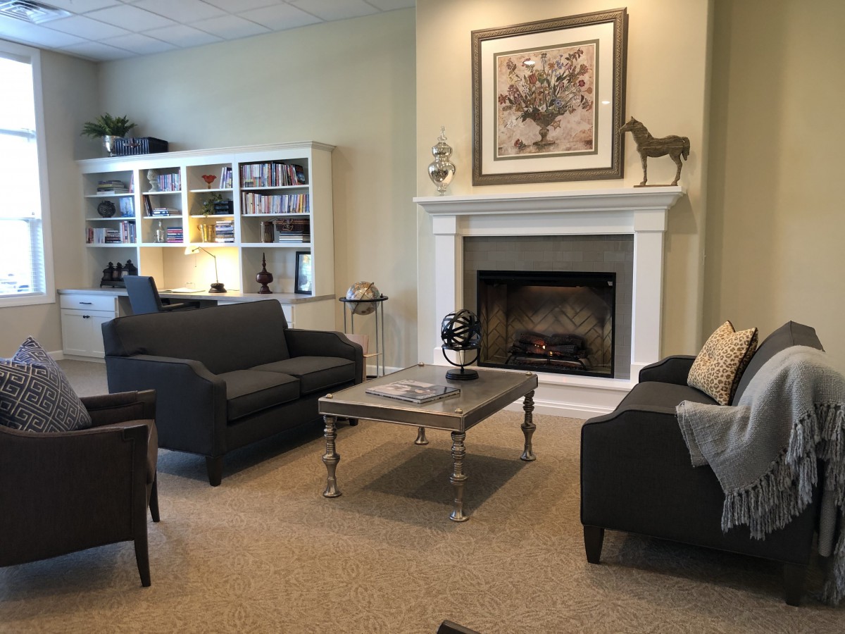 A cozy living room with sofas, a coffee table, bookshelf, and a fireplace.