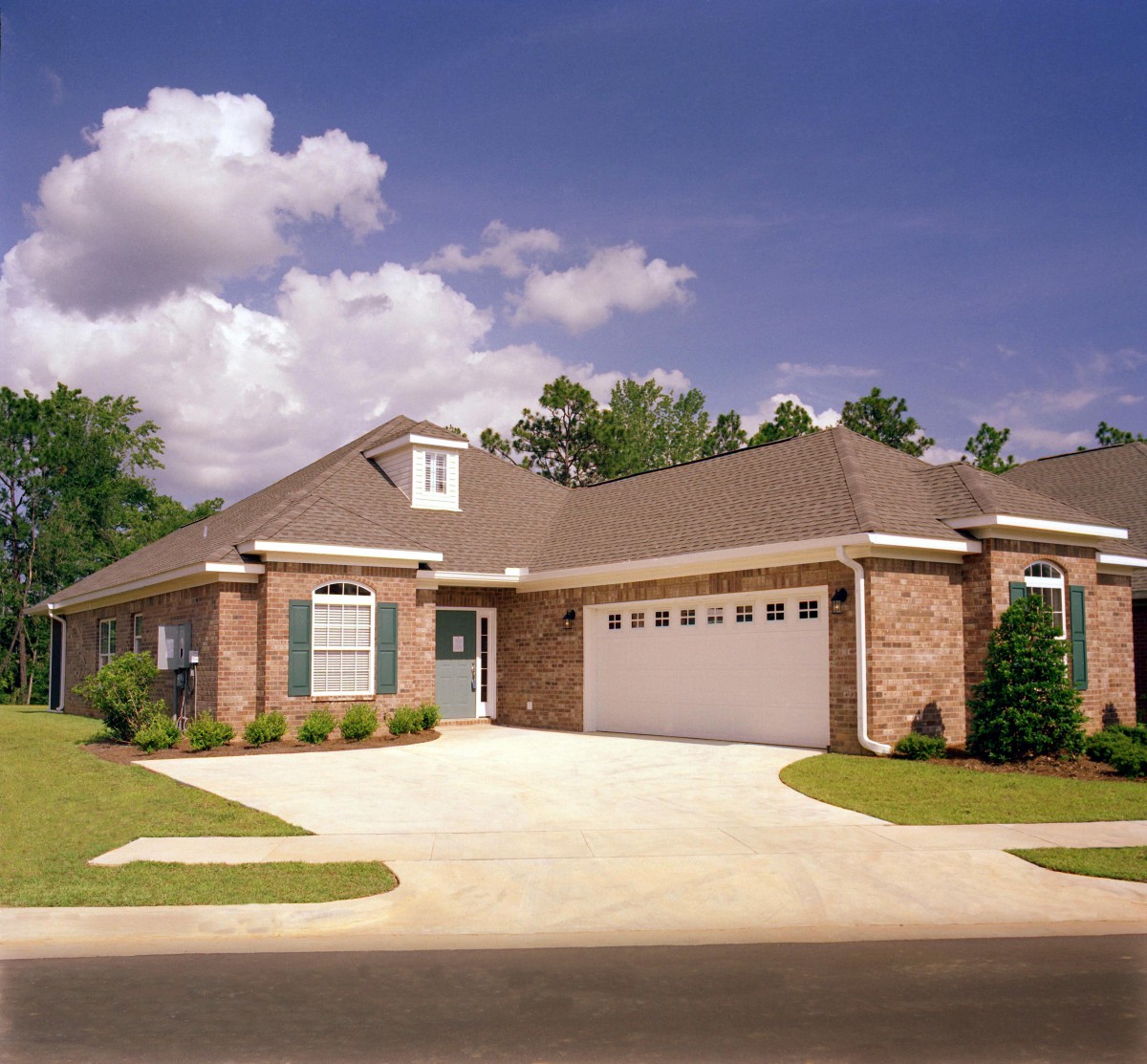 A suburban brick house with a driveway and attached garage.