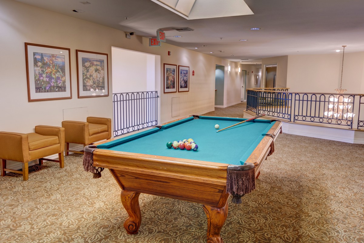 A cozy recreation room featuring a billiards table, surrounded by framed artwork and comfortable seating.