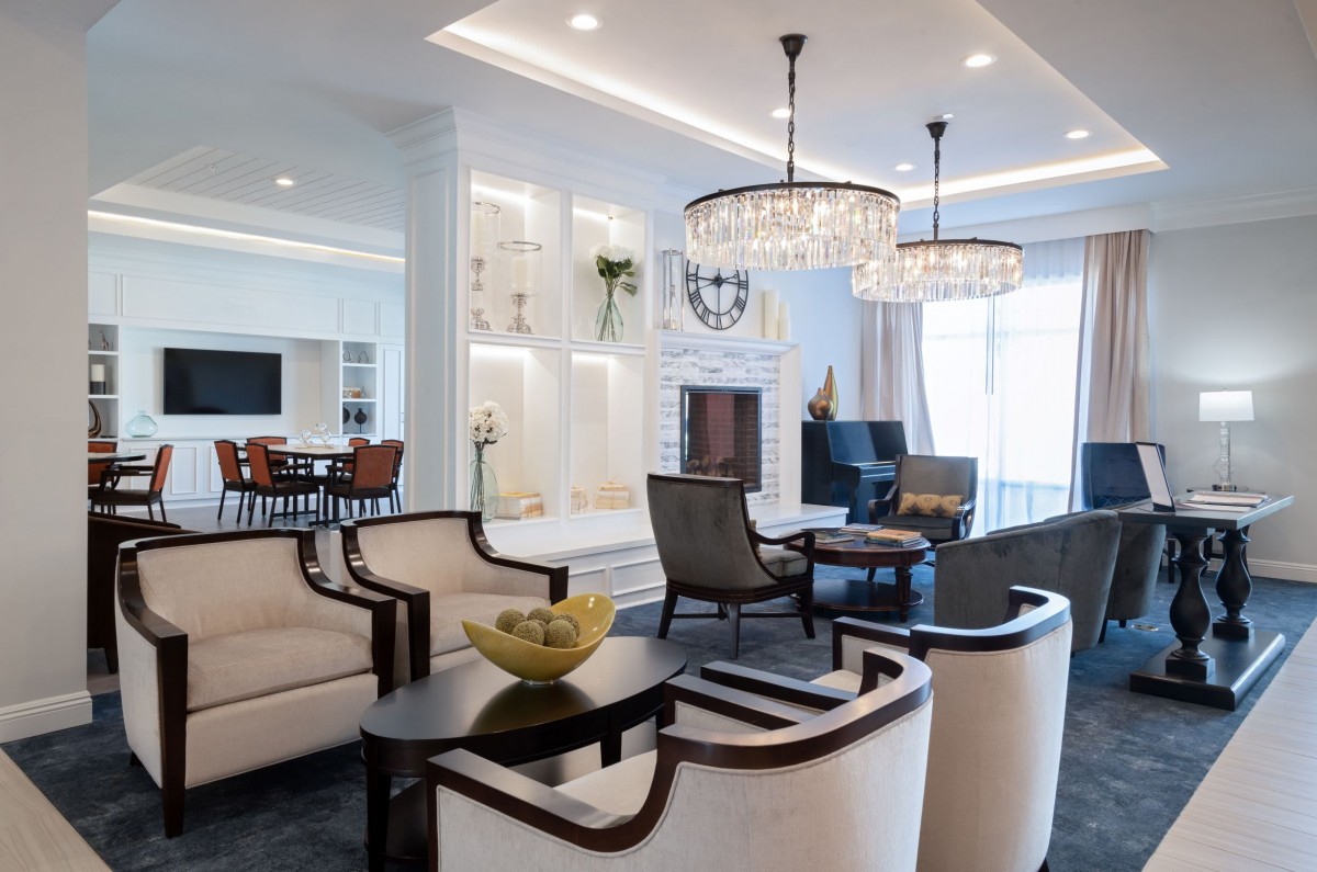 A modern living room with elegant chandeliers, comfortable seating, and a cozy fireplace.