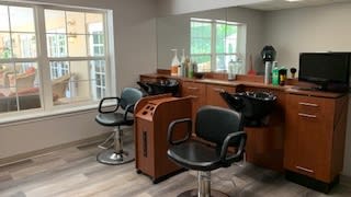 A modern hair salon interior with chairs, mirrors, and washing stations.