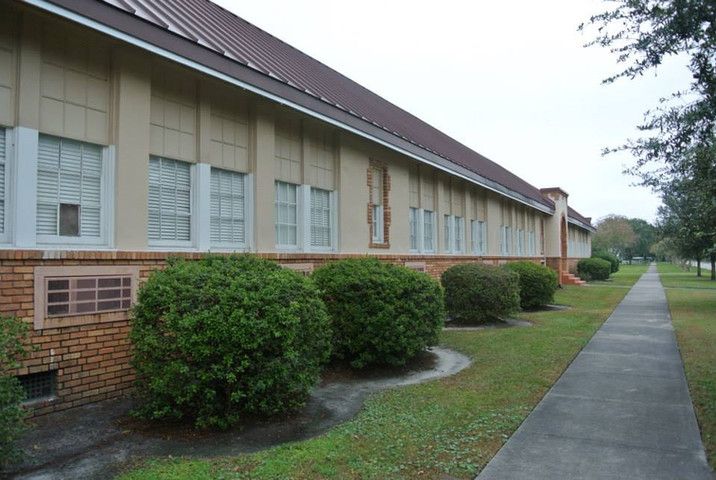Exterior view of a building with bushes and a lawn.