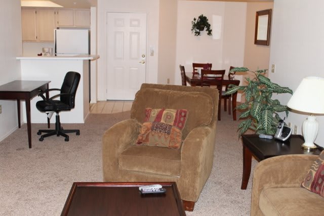 A cozy living room with a comfortable armchair and a view into the dining area.