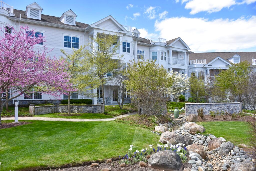 A scenic view of a residential apartment building surrounded by landscaped gardens and trees in springtime.