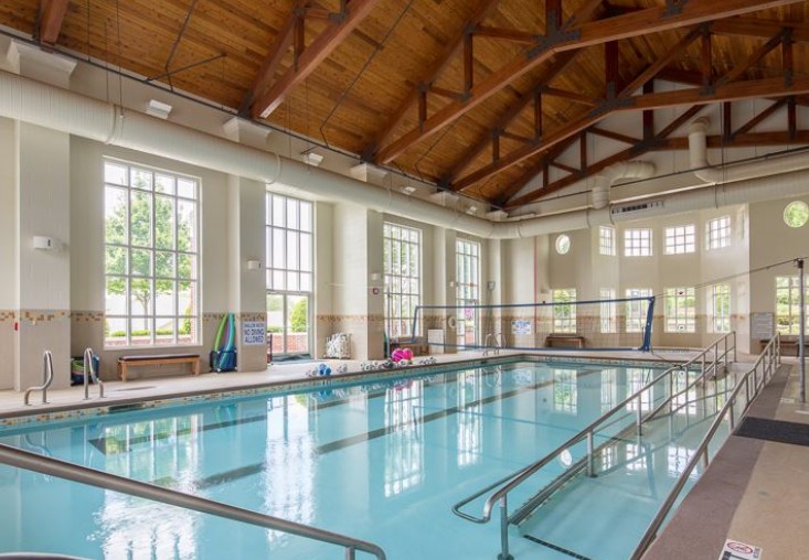 An indoor swimming pool with large windows and a wooden vaulted ceiling.