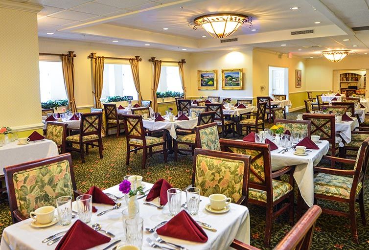 An elegant dining room with beautifully set tables, featuring floral arrangements and decorative elements.