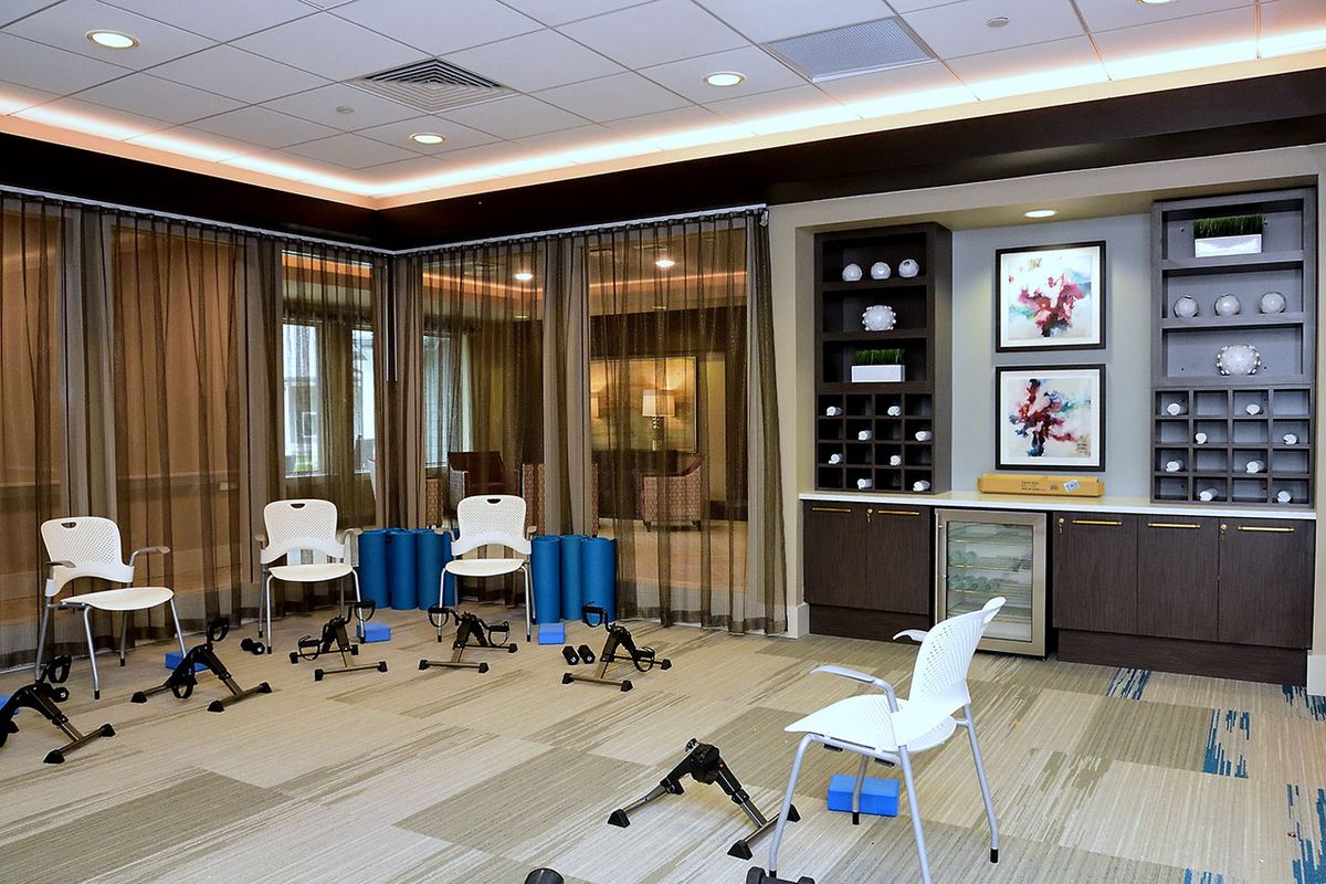 A modern yoga and exercise studio featuring chairs and fitness equipment.