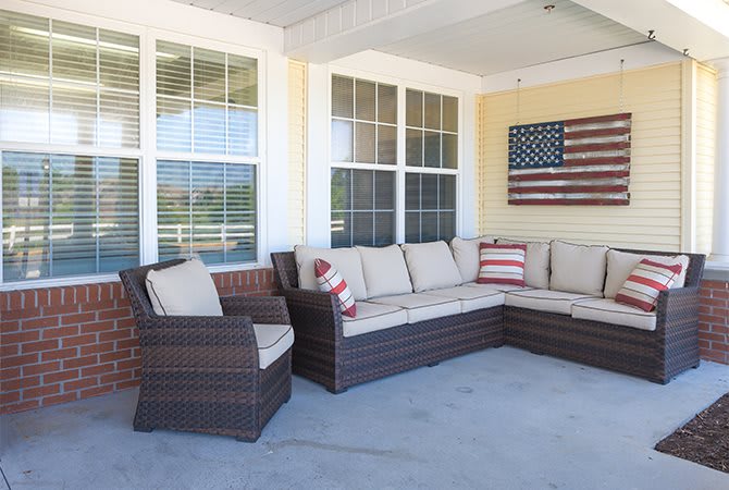 A cozy patio with wicker outdoor furniture and an American flag decoration.