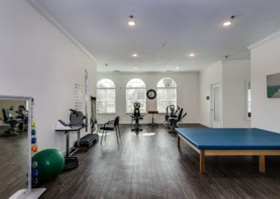 A spacious physical therapy room equipped with exercise machines and a treatment table.