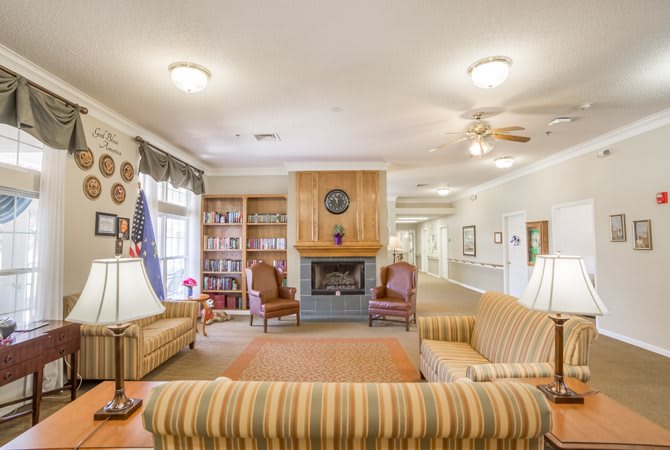 A cozy living room with a fireplace, striped sofas, and bookshelves lining the walls.