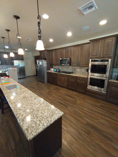 A spacious modern kitchen featuring granite countertops, wood cabinets, and stainless steel appliances.