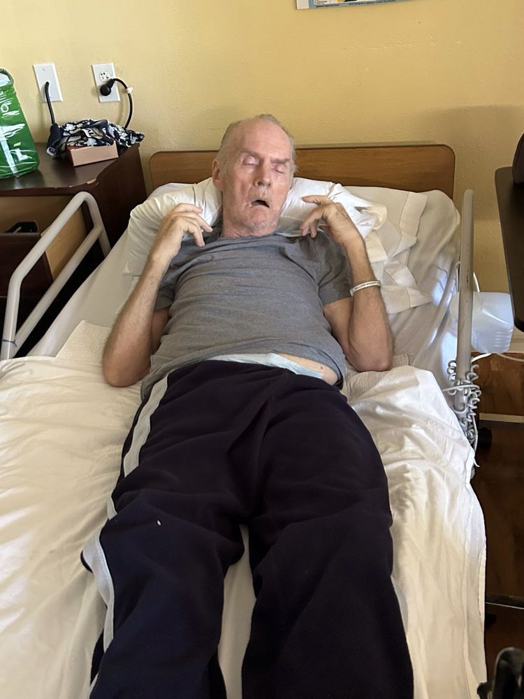 An elderly man resting in a hospital bed in a medical setting.