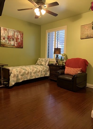 A cozy bedroom featuring a single bed, armchair, and decorative wall art.