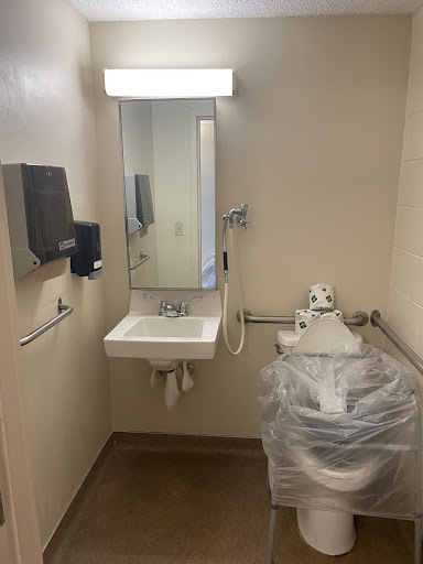 A clean and accessible bathroom featuring a sink, mirror, hand dryer, and toilet.
