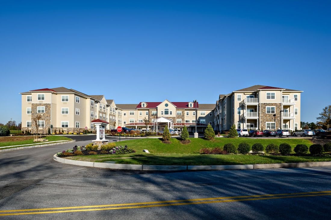 A modern apartment complex with landscaped grounds under a clear blue sky.