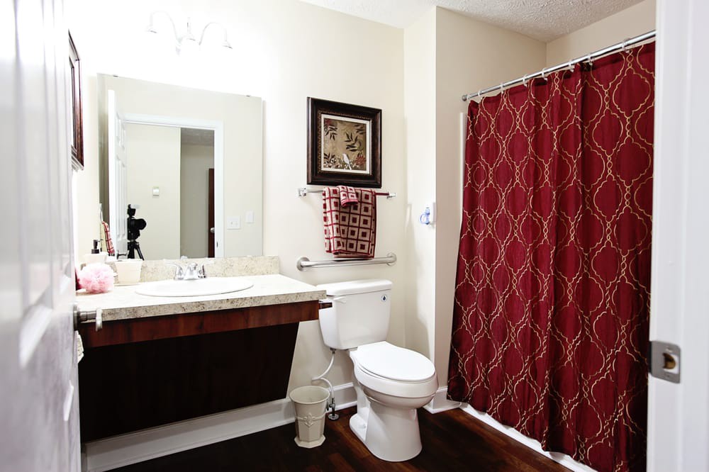 A modern bathroom with red patterned shower curtain and matching decor.
