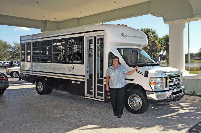 A person standing next to a white bus in an outdoor setting.