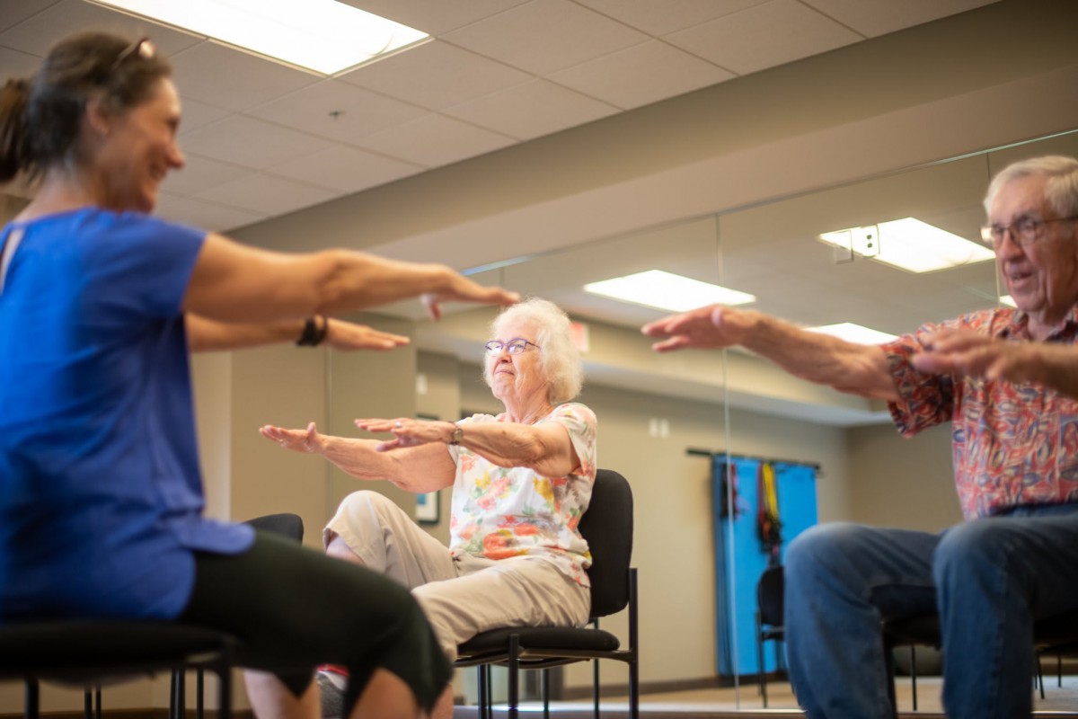 A group of seniors participating in a seated exercise class.