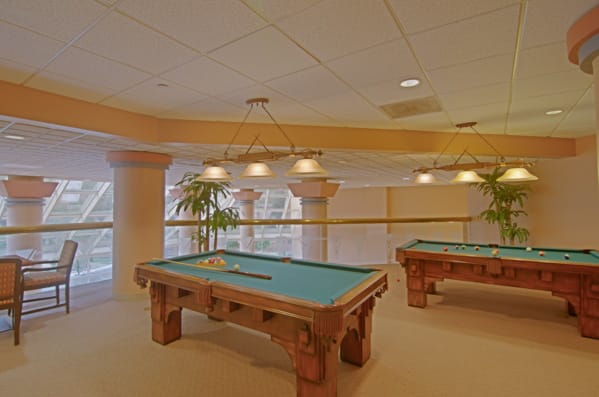 An indoor game room featuring multiple pool tables with ceiling lighting.