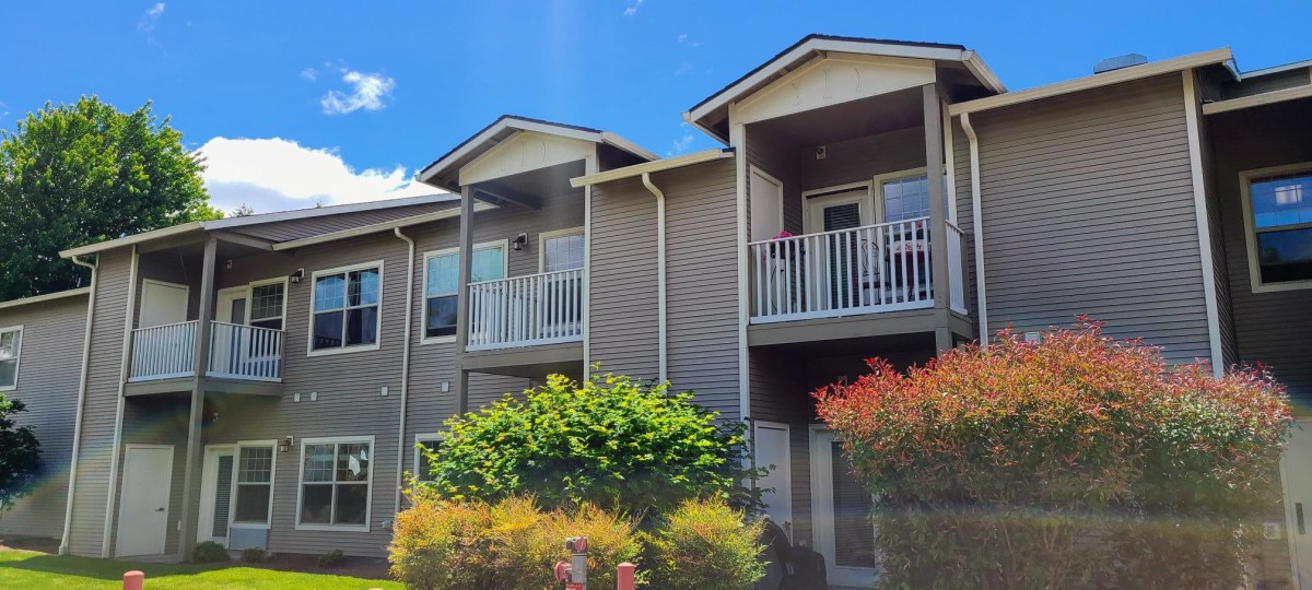 A modern apartment building with balconies under a clear blue sky.