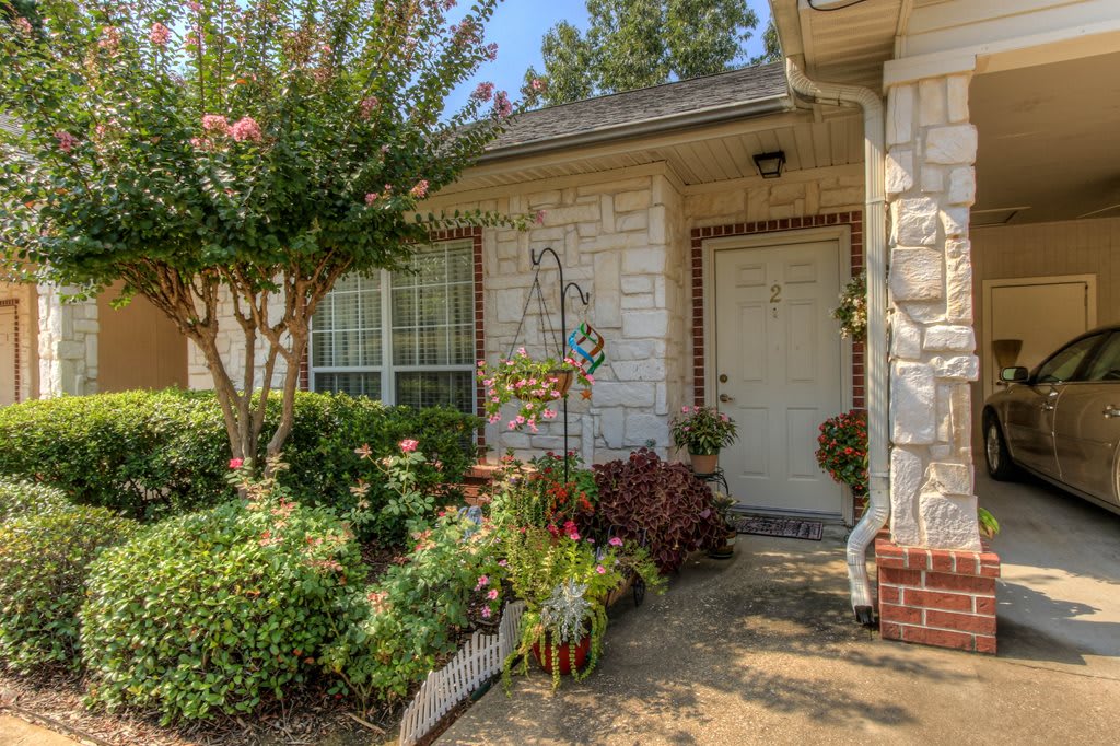 A charming house entrance surrounded by a lush garden and various plants.