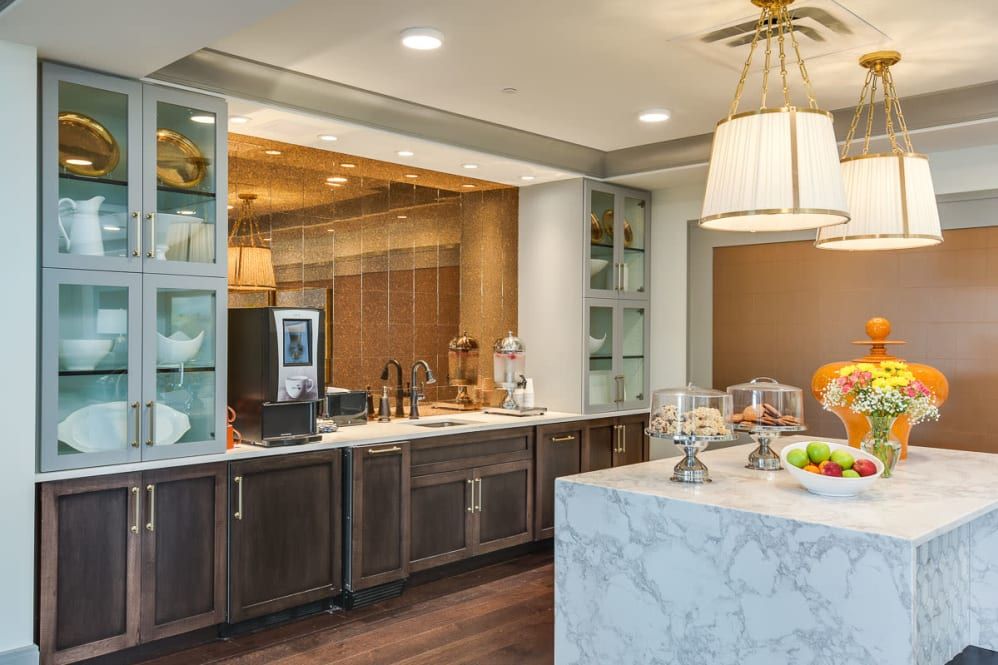 A modern kitchen featuring marble countertops, dark wood cabinetry, and stylish pendant lighting.