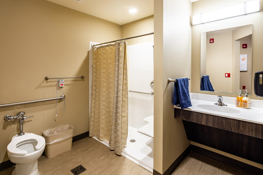 A clean and modern bathroom featuring a shower area, sink, and neatly hung towels.