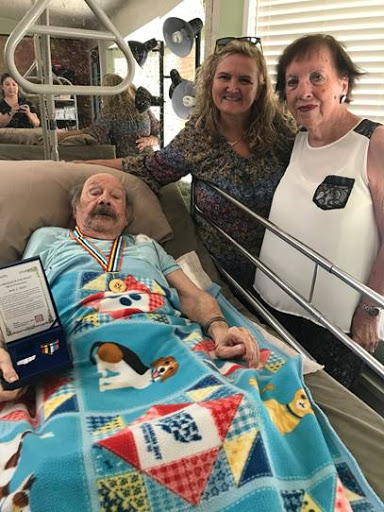 A heartwarming moment in a hospital room, where family members gather around a patient adorned with medals.