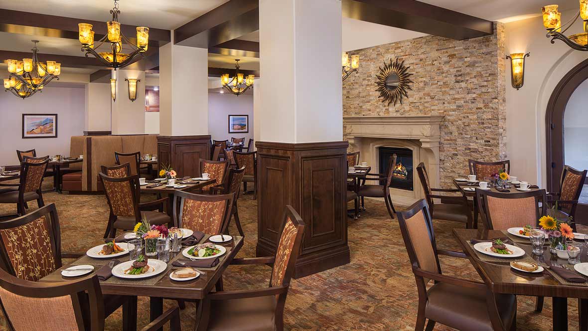 A cozy restaurant dining area with elegantly set tables and a decorative fireplace.