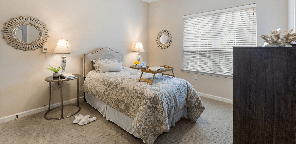 A cozy bedroom with a single bed, bedside lamp, and window.