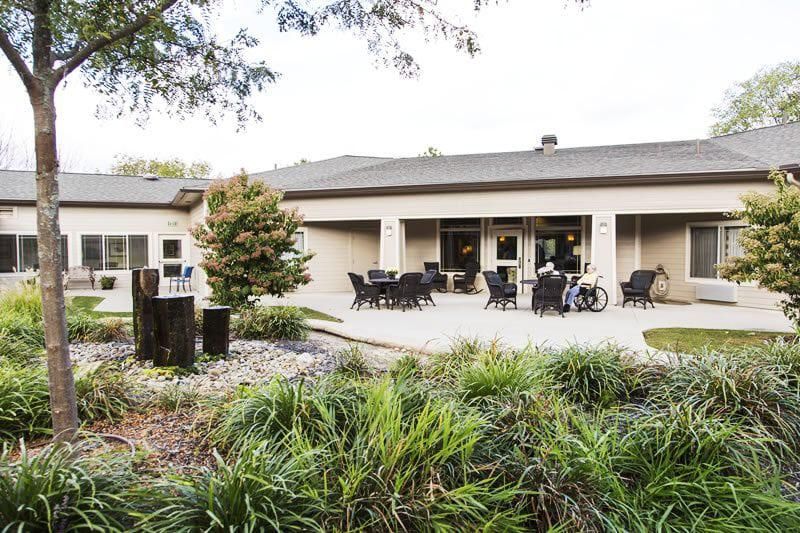 A cozy outdoor patio area with tables and chairs, surrounded by lush greenery.
