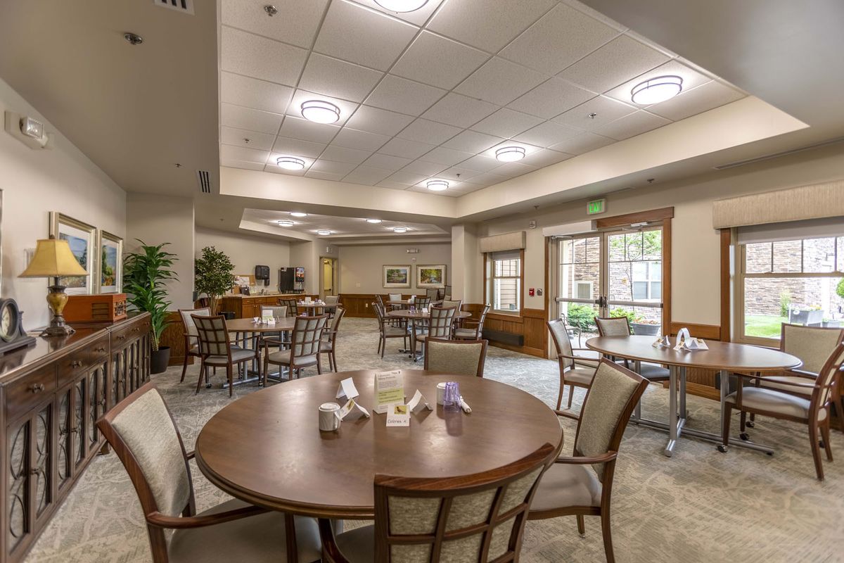 A modern dining area with round tables and chairs, featuring ample lighting and large windows.