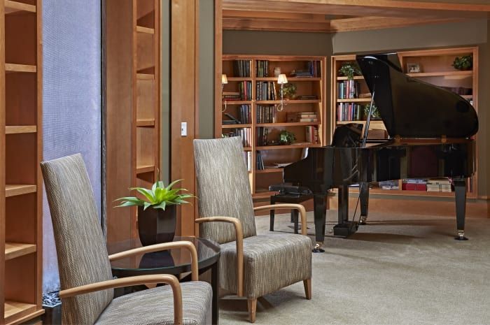 A cozy library setting with a piano and comfortable seating.