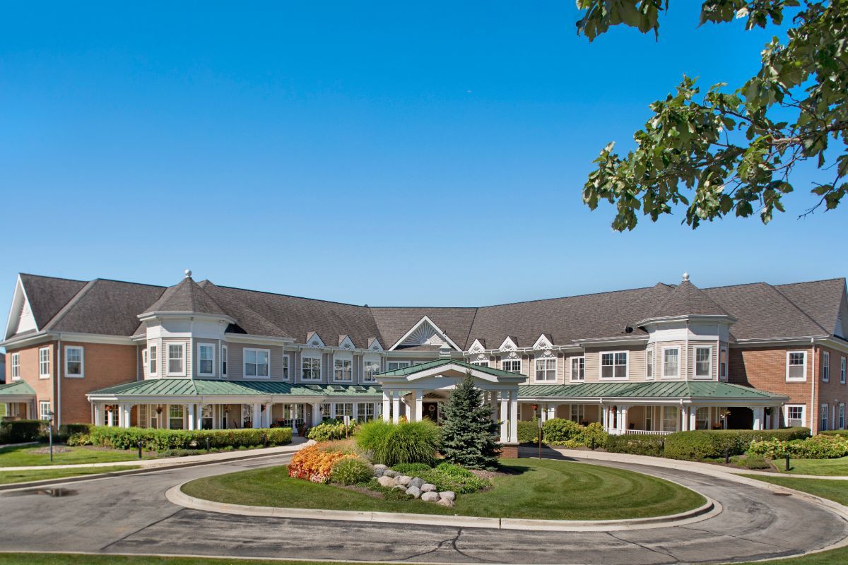 A large residential building with a circular driveway and landscaped front yard.