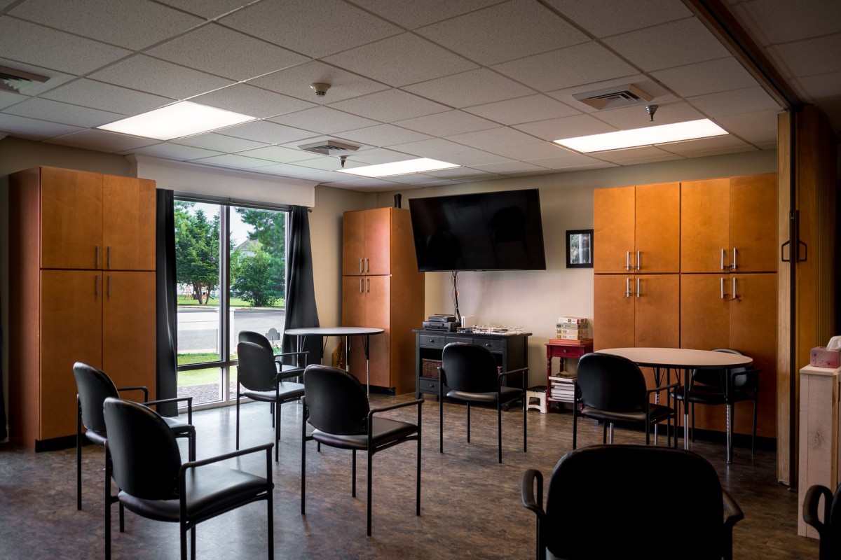 A conference room with chairs arranged for a meeting, featuring a large television and wooden cabinets.