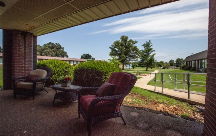 A cozy patio area with outdoor furniture overlooks a lush garden and winding pathway.