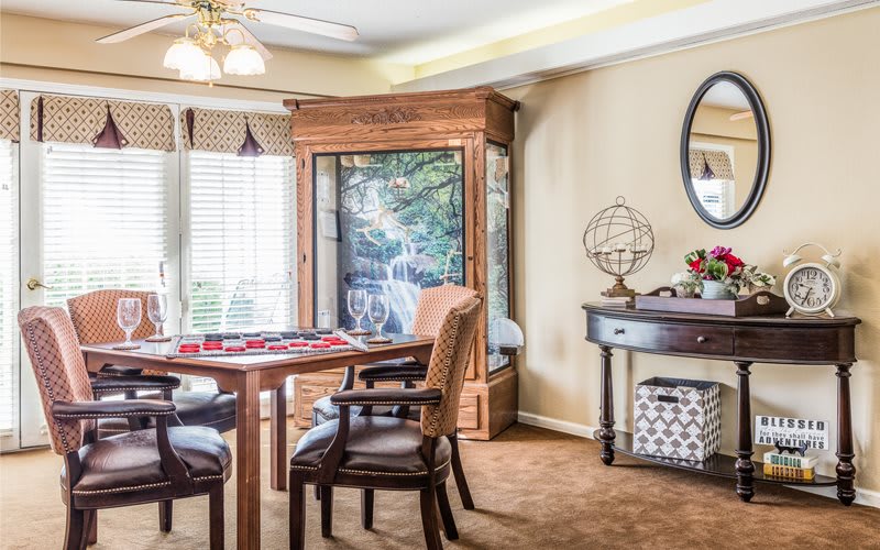 A cozy living room with classic furniture and elegant decor features a round table with chairs, a wooden cabinet, and a decorative globe.