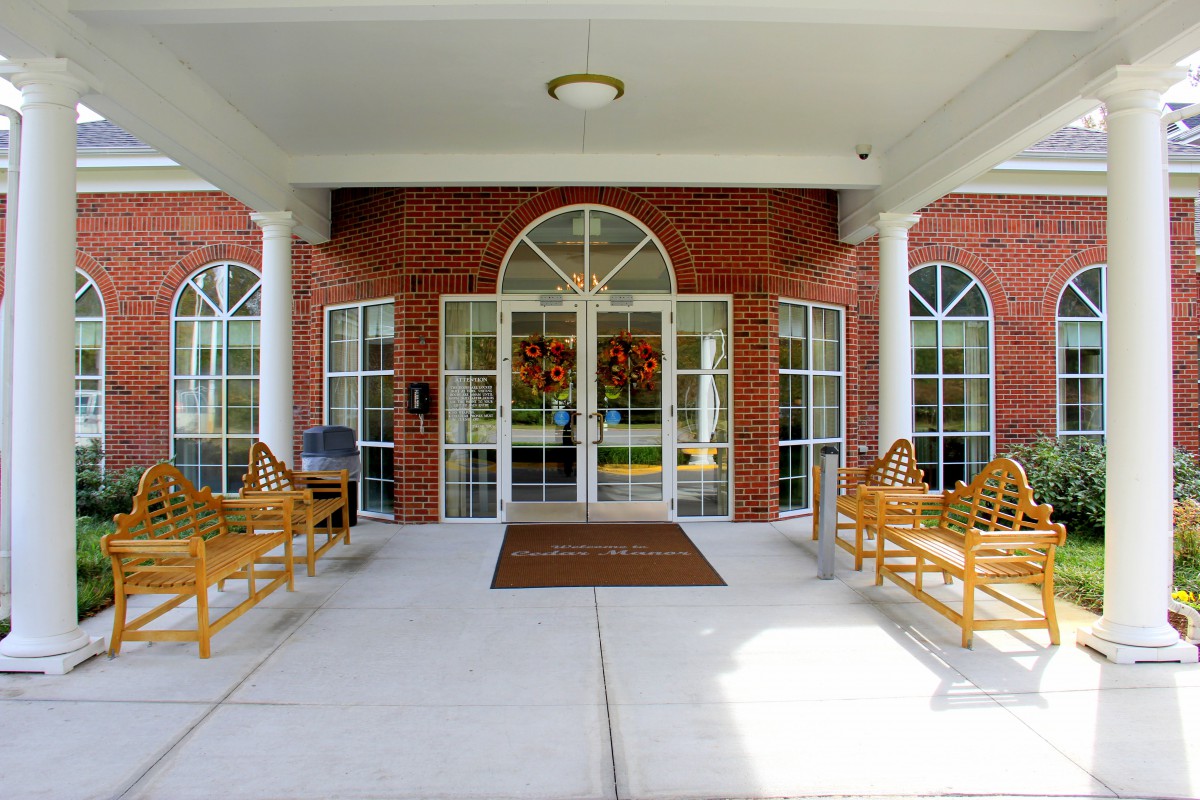 The entrance of a building featuring symmetrical benches and large windows.