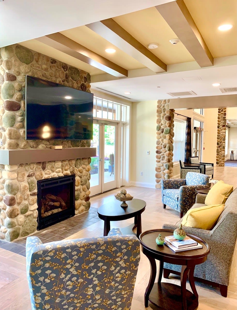 A cozy and modern living room featuring a stone fireplace and ample natural light.
