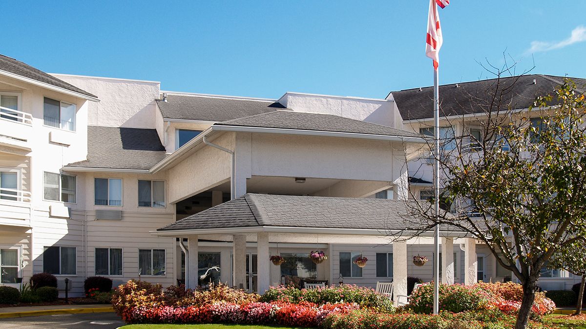 A well-maintained residential building with an American flag and landscaped garden.