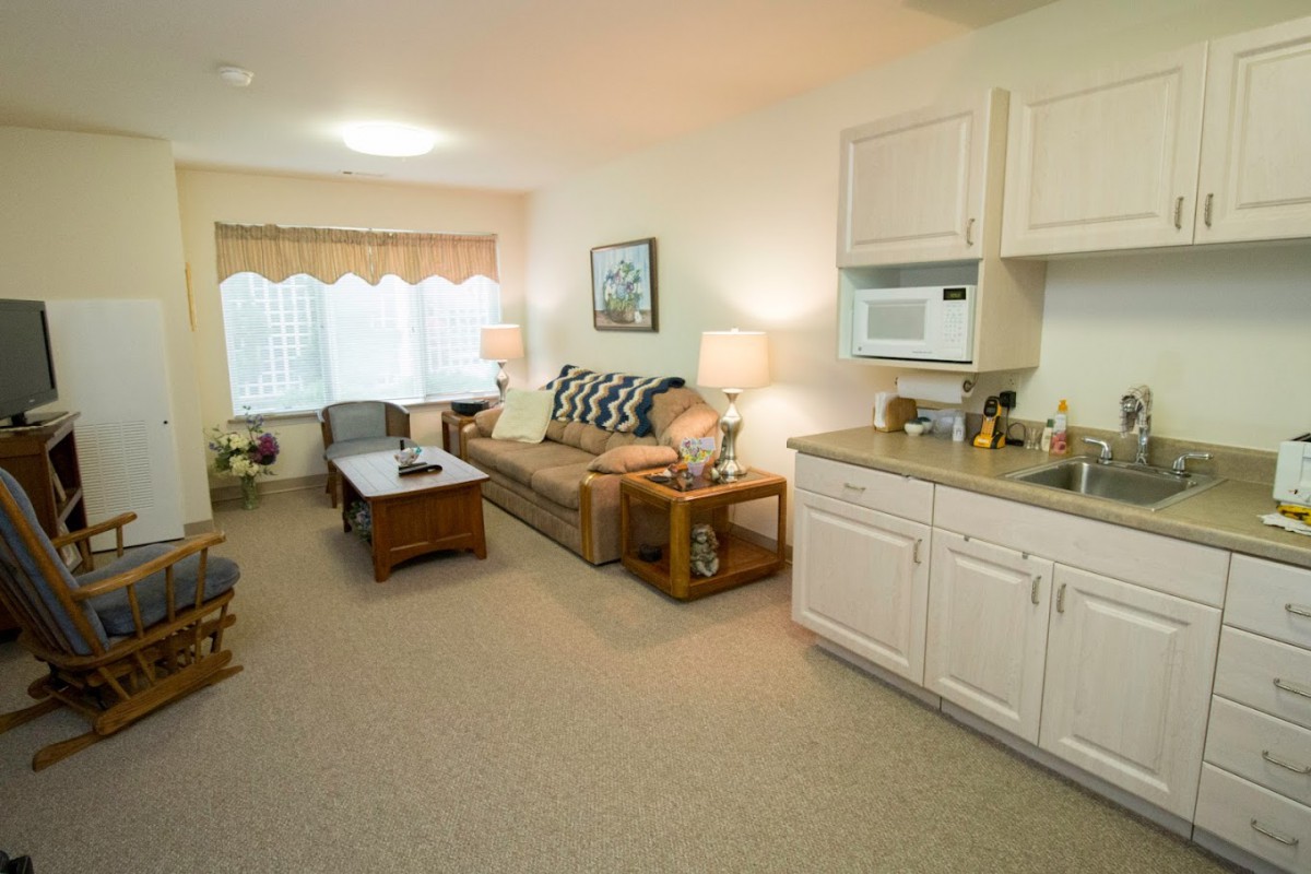 A cozy living room with a sofa, coffee table, and kitchenette.