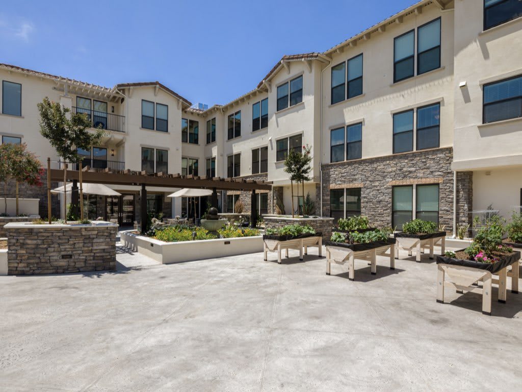 A modern three-story apartment building with a spacious courtyard.