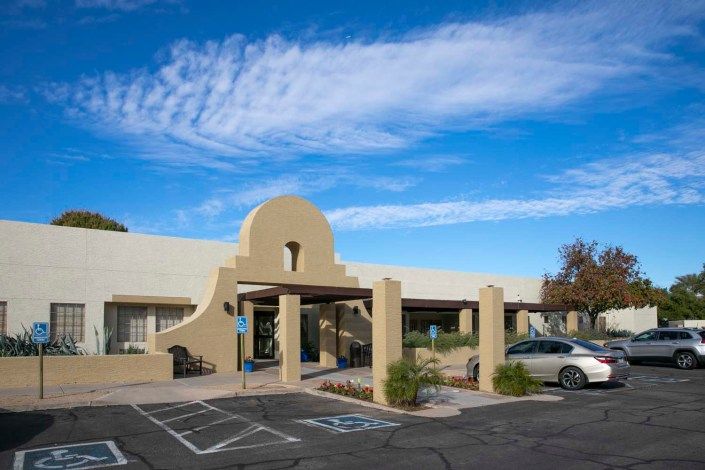 A southwestern-style building with a parking lot under a blue sky.