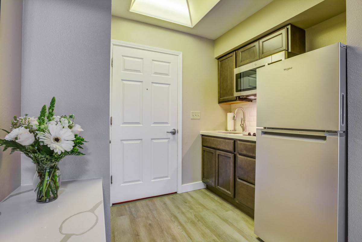 A modern kitchen with wooden cabinets, a refrigerator, and a microwave.