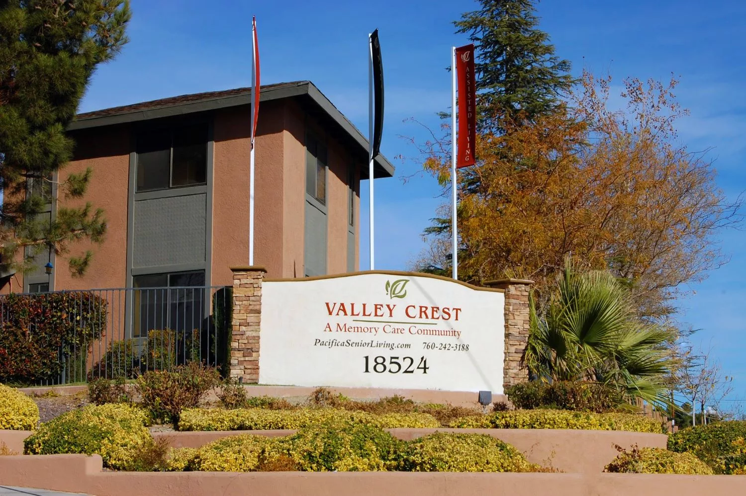Business sign for Valley Carpet in front of a commercial building, with flags and landscaping.