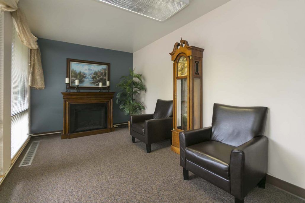 A cozy waiting room with leather armchairs, a fireplace, and a grandfather clock.