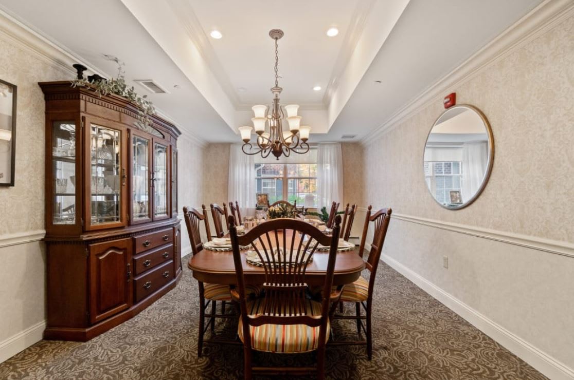 A well-decorated dining room with a large wooden table, chairs, and an elegant chandelier.