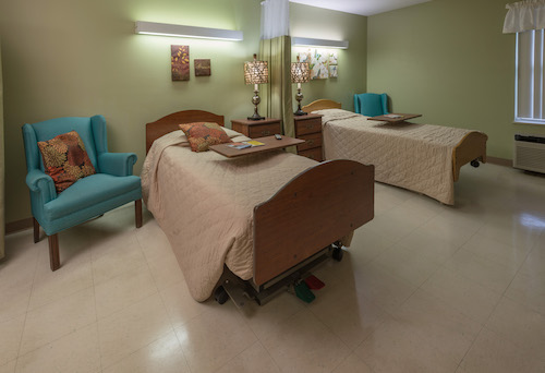 A cozy bedroom featuring two beds, a comfortable armchair, and decorative elements.